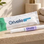 Penna Orivelle con la confezione su un ripiano chiaro accanto a un asciugamano